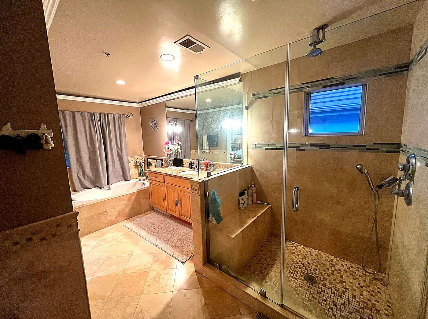 Master bathroom with soaking tub, travertine tile, custom vanity, and a frameless glass walk-in shower.