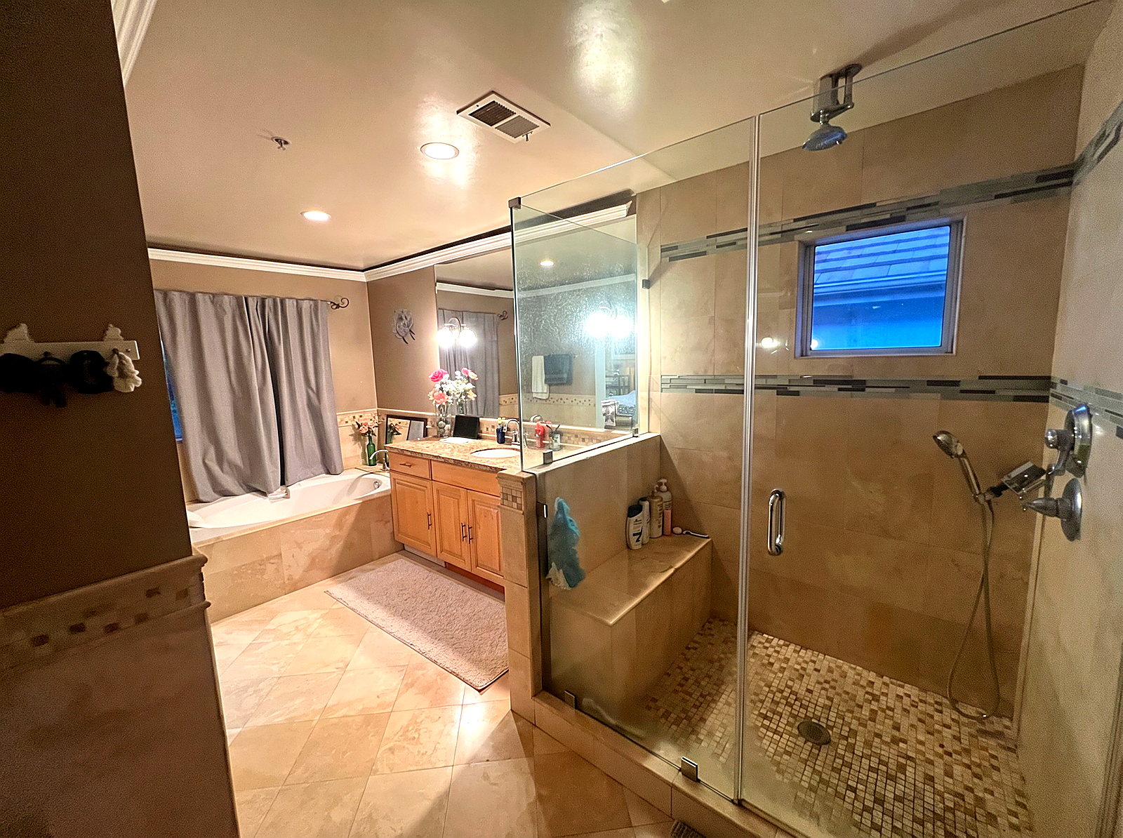 Master bathroom with soaking tub, travertine tile, custom vanity, and a frameless glass walk-in shower.