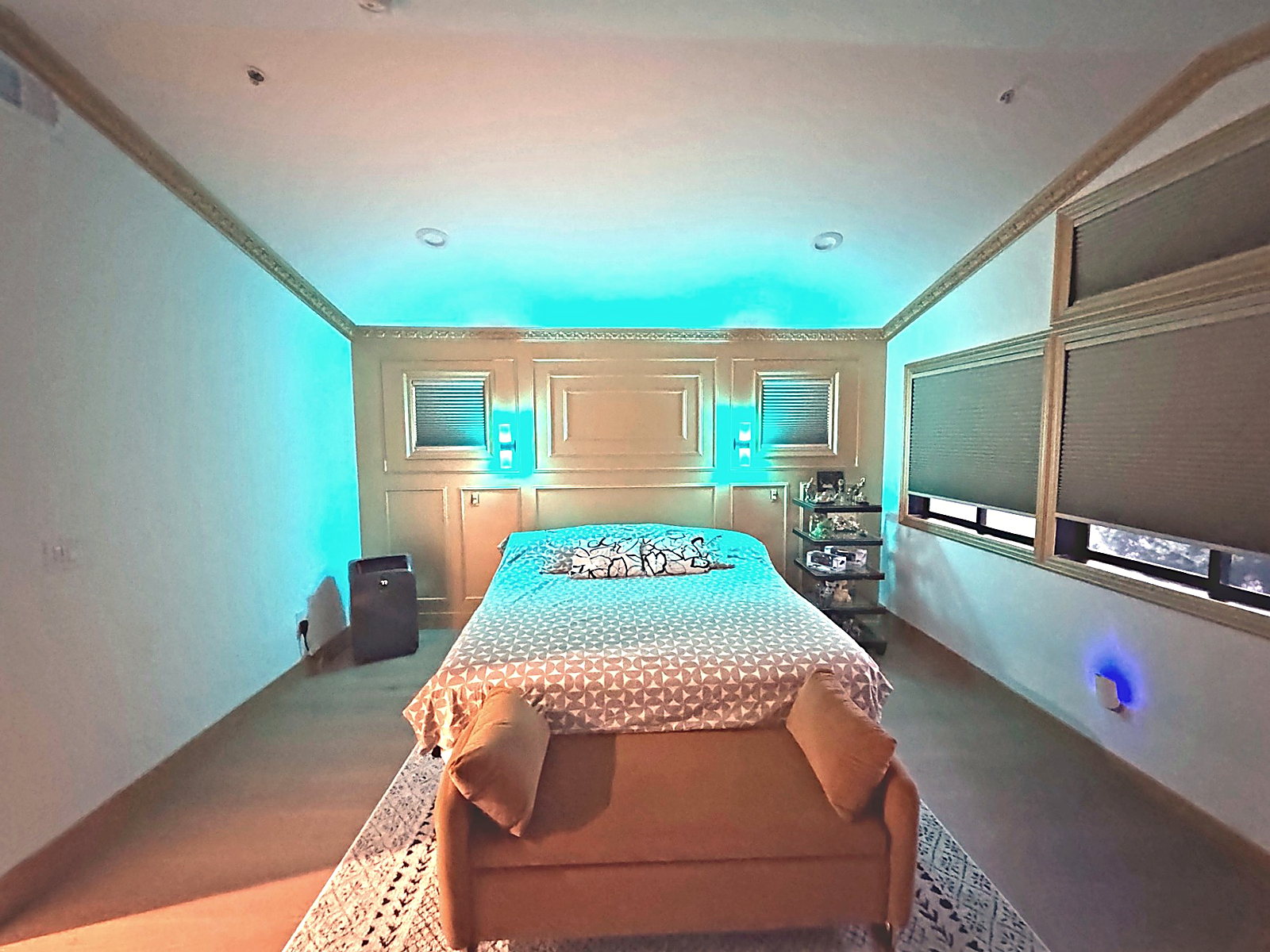 Bedroom with custom trim package and soft accent lighting around the ceiling and wall sconces.
